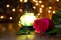 Red rose and lantern with lights on a wooden table Royalty Free Stock Photo