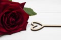 Red rose with leaves and hollow wooden heart on white wooden background. Valentine`s day or Love concept. Royalty Free Stock Photo