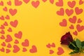 a red rose lies on a yellow background. Lots of red cardboard hearts of different sizes. Copy space. Valentine's Day