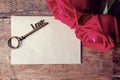 Red rose and love alphabet shape key with paper card on wooden floor. Retro color simulation