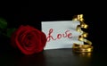 Red rose, love inscription, golden ribbon on a black background. Background for Valentine`s Day