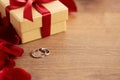 Red rose petals, gift box and wedding rings on wooden background