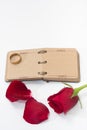 Red rose petals with opened antique diary and golden ring