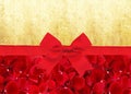 Red rose petals and red ribbon with bow over old paper Royalty Free Stock Photo
