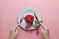 Red rose on white dish, Couple ring inside, with hand holding fork and knife, on pink background, Concept of Valentine`s Day Royalty Free Stock Photo