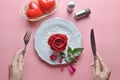 Red rose on white dish, with hand holding fork and knife, And couple heart in white basket, On pink background. Royalty Free Stock Photo