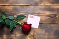 Red rose on wooden background with copyspace and sticker with a paper clip and heart, a reminder on a note sheet. Gift for woman Royalty Free Stock Photo