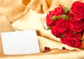 Red roses and blank card on golden satin