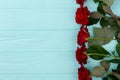 Red roses border, colorful wooden background.