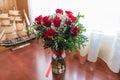 Red roses bouquet with glass vase on wooden table and curtains background Royalty Free Stock Photo