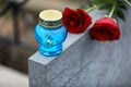 Red roses and candle on light grey tombstone outdoors. Funeral ceremony Royalty Free Stock Photo