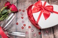 2 red roses with champagne flutes and a heart shaped gift box. Royalty Free Stock Photo