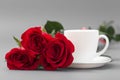 Red roses with a coffee cup of white color on a gray background Royalty Free Stock Photo