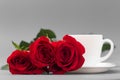 Red roses with a coffee cup of white color on a gray background Royalty Free Stock Photo