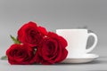 Red roses with a coffee cup of white color on a gray background Royalty Free Stock Photo