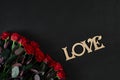 Red roses flowers with wooden word LOVE on black background with Royalty Free Stock Photo