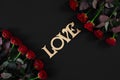 Red roses flowers with wooden word LOVE on black background with Royalty Free Stock Photo