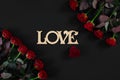 Red roses flowers with wooden word LOVE on black background with Royalty Free Stock Photo