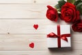 red roses and gift box with bow on white wooden background top view, valentines day floral template with copy space Royalty Free Stock Photo