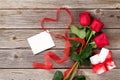 Red roses, gift box and heart shape ribbon over wood