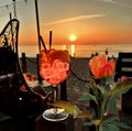 Red roses and glass of wine  with ice  on wooden table top    sunset at sea  in beach restaurant view in pink sky and se Royalty Free Stock Photo