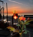 Tropical Red roses and glass of wine  with ice  on wooden table top    sunset at sea  in beach restaurant view in pink sky and se Royalty Free Stock Photo