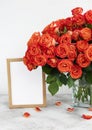 Red roses in a glass vase with an empty photo frame Royalty Free Stock Photo