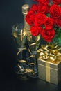 Red roses, golden gift box and and champagne on black background Royalty Free Stock Photo