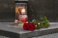 Red roses and grave light on grey granite tombstone outdoors, space for text. Funeral ceremony Royalty Free Stock Photo