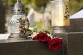 Red roses and grave light on grey granite tombstone outdoors. Funeral ceremony Royalty Free Stock Photo