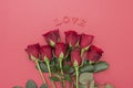 Red roses and LOVE letters inscription, over pink background flat lay. Valentine`s Day, Birthday abstract background Royalty Free Stock Photo