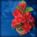 Red roses made of fabric in a vase on a blue cloth. Royalty Free Stock Photo