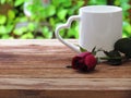 Red roses placed in front of white glass with heart-shaped handle on wooden table Royalty Free Stock Photo