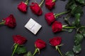 Red roses and white open gift box on black colored paper background , top view Royalty Free Stock Photo