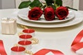 Red Roses on a white plate, candles and giftbox. Romantic composition for Valentine`s Day, Anniversary, Events. Place Royalty Free Stock Photo