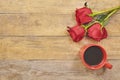 Red rosesand cup of coffee on wooden background with copy space. Top view