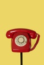 Red rotary dial telephone on a black stand