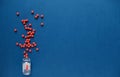 Red round, balls, pills spill out of an inverted transparent bottle with pills on blue background Royalty Free Stock Photo