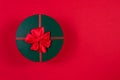 Red round gift box with a red bow on a green lid on a red background. View from above. Place for an inscription. The Royalty Free Stock Photo