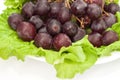 Red round grapes with salad fresh green leaves on light ceramic plate isolated white background Royalty Free Stock Photo