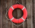 Red and round lifebuoy hanging on brown wooden wall