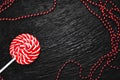 Red round Lollipop on black background with texture near beads of red color