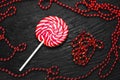 Red round Lollipop on black background with texture near beads of red color