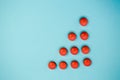 Red round medical pharmaceutical drug pills lie in the shape of a triangle or arrow on a blue background Royalty Free Stock Photo