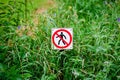 Red round prohibition sign with a black silhouette of a man crossed out. Prohibition to walk on the grass