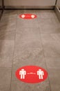 Red round sign printed on ground at supermarket cash desk register informing people to keep 2 meter 6 feet distance from Royalty Free Stock Photo