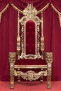 Red royal chair on a background of red curtains. Royalty Free Stock Photo