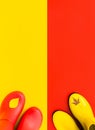 Two pair of colourful rubber boots standing on yellow and red background. Royalty Free Stock Photo