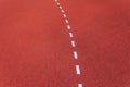 Red running track with dividing white line. Red stone grain texture with white line closeup