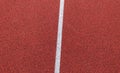 Red running track made of rubber. Red stone grain texture with white line closeup